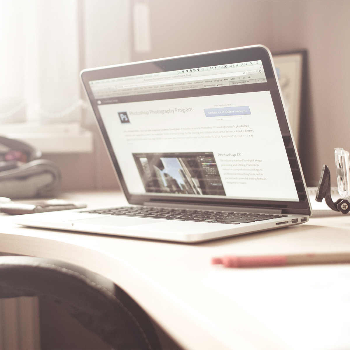 A MacBook Pro on a bright office desk, open to a photography program page